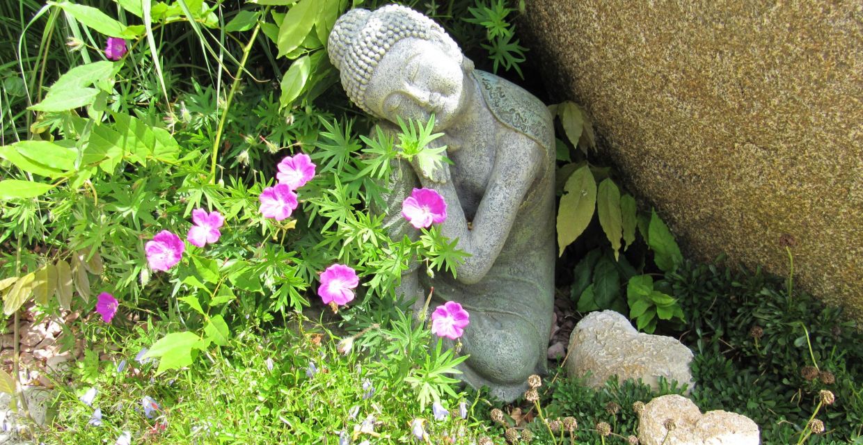Buddha mit Steinherzen im Garten